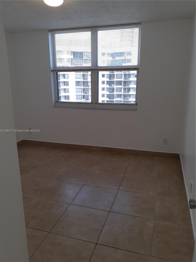 unfurnished room featuring a textured ceiling and tile flooring