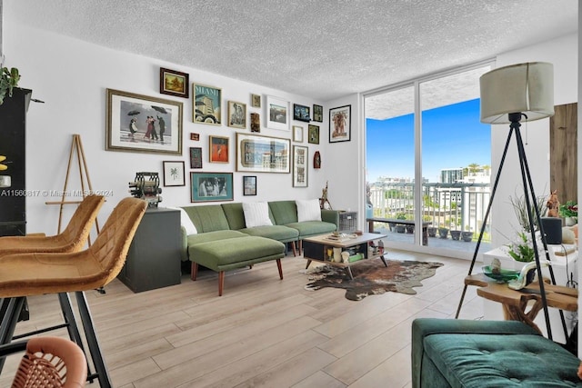 living room with a textured ceiling, light wood-type flooring, and expansive windows