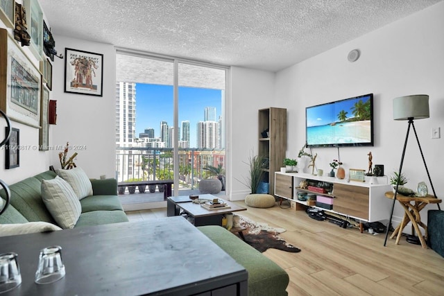 living room with a wall of windows, a textured ceiling, and light wood-type flooring