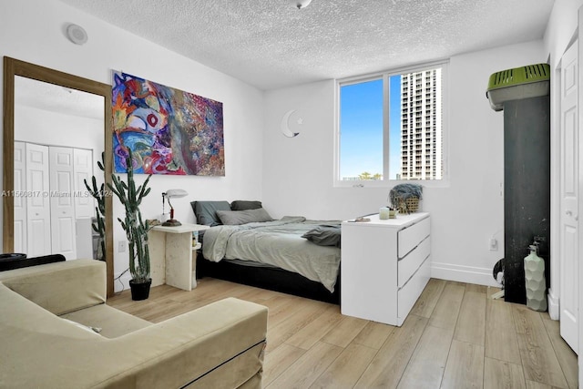 bedroom with a closet, light hardwood / wood-style flooring, and a textured ceiling