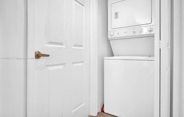 clothes washing area with hardwood / wood-style flooring and stacked washer / drying machine