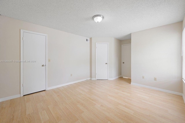 spare room featuring light hardwood / wood-style floors and a textured ceiling