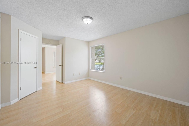 unfurnished room with light hardwood / wood-style floors and a textured ceiling