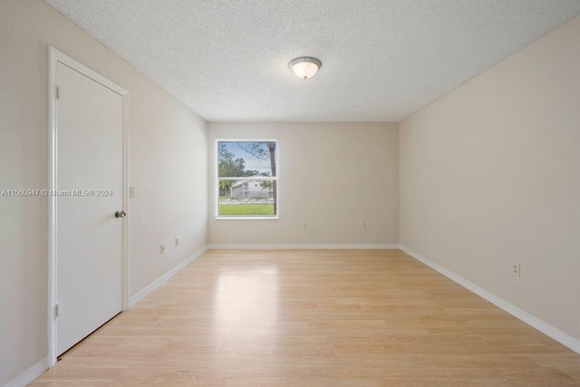 empty room with a textured ceiling and light wood-type flooring