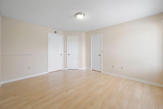 unfurnished room featuring a textured ceiling and light wood-type flooring