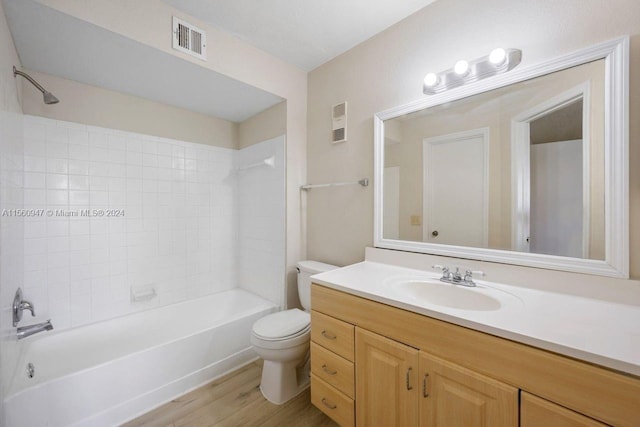 full bathroom featuring vanity with extensive cabinet space, hardwood / wood-style floors, toilet, and tiled shower / bath