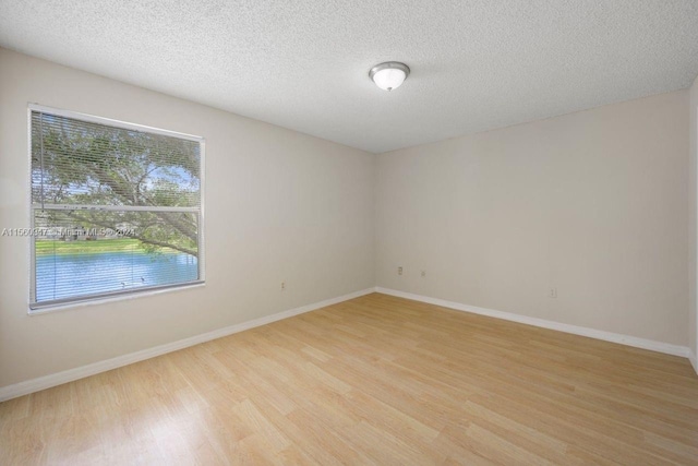 empty room with a textured ceiling and light hardwood / wood-style floors