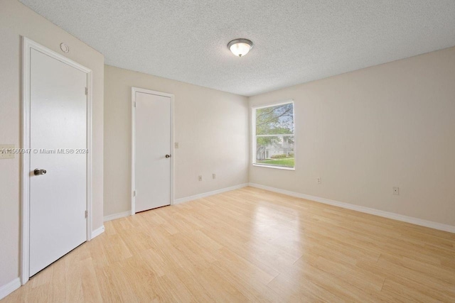 unfurnished room featuring a textured ceiling and light wood-type flooring