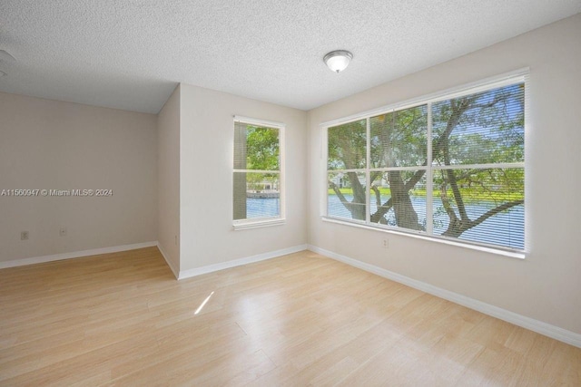 spare room with light hardwood / wood-style flooring and a textured ceiling