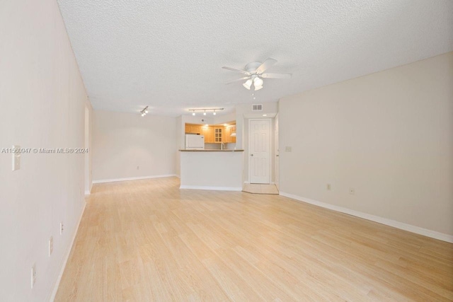 unfurnished living room with ceiling fan, a textured ceiling, light hardwood / wood-style flooring, and rail lighting