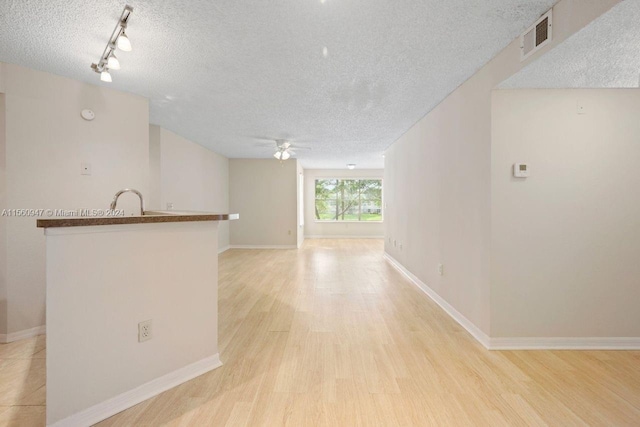 interior space with ceiling fan, sink, track lighting, a textured ceiling, and light wood-type flooring