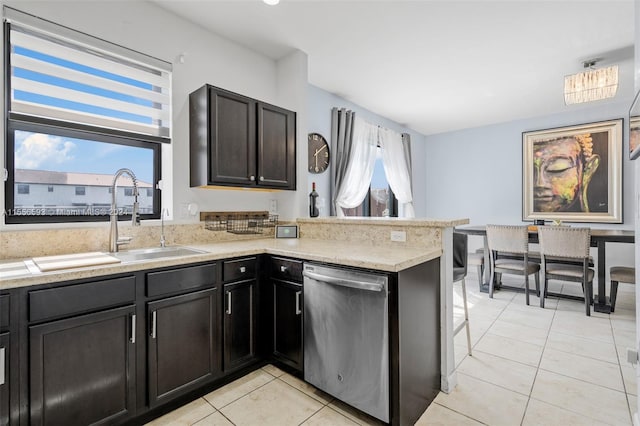 kitchen with kitchen peninsula, sink, stainless steel dishwasher, light tile flooring, and light stone countertops