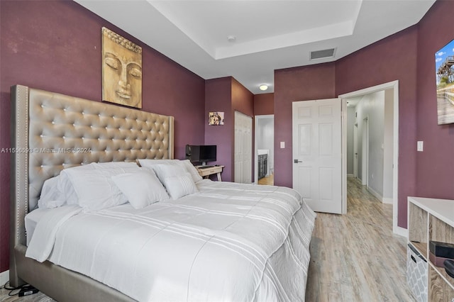 bedroom featuring light hardwood / wood-style floors and a raised ceiling