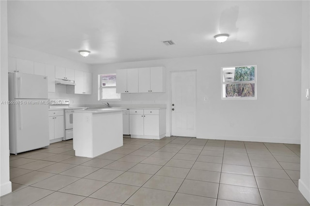 kitchen with white cabinets, white appliances, light tile floors, and a kitchen island