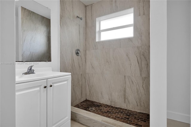 bathroom with tiled shower and vanity