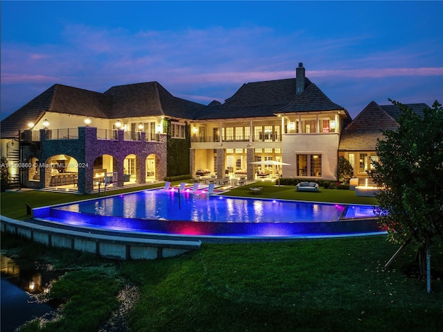 pool at dusk featuring a yard and a patio area