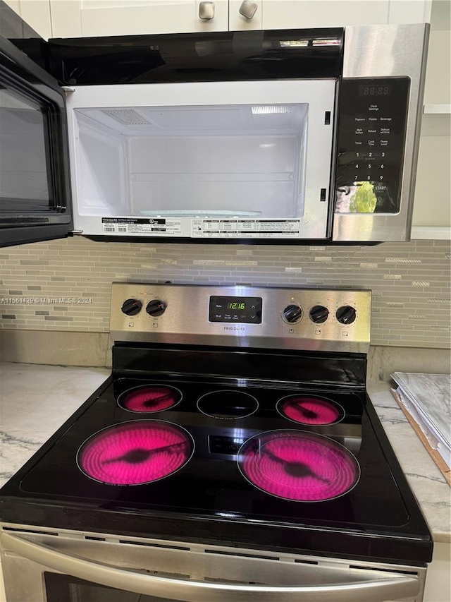 interior details featuring electric range, white cabinetry, and backsplash