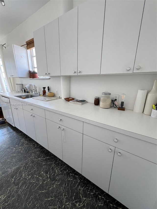 kitchen with white cabinets, sink, and dark tile flooring