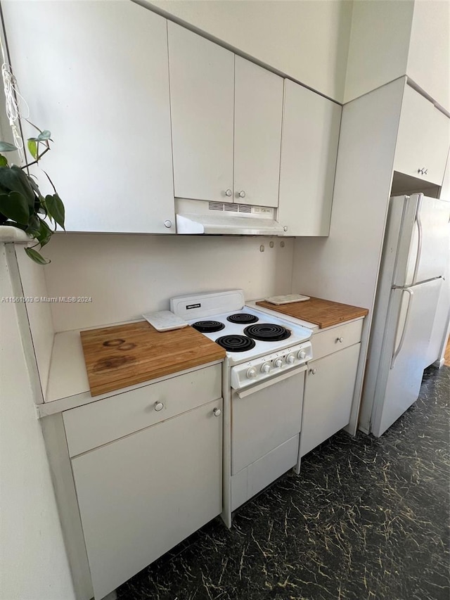 kitchen with white appliances, wood counters, dark tile flooring, and white cabinetry