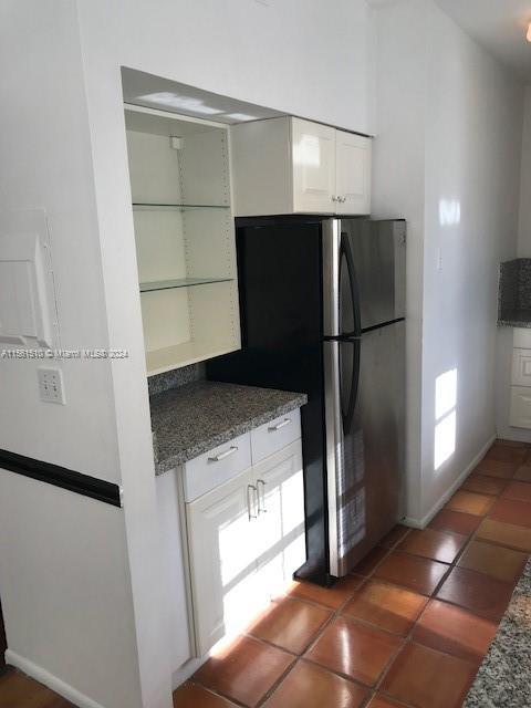 kitchen featuring stainless steel fridge, tile flooring, and white cabinets