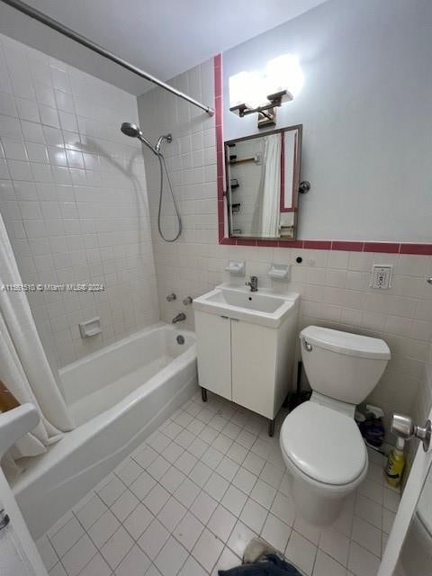 full bathroom with tile walls, shower / tub combo with curtain, tile floors, toilet, and vanity