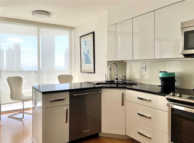 kitchen with hardwood / wood-style floors, appliances with stainless steel finishes, sink, and kitchen peninsula