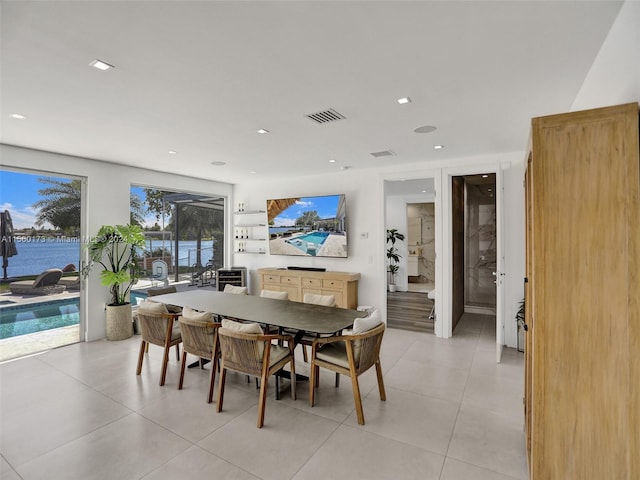 dining room featuring a water view, light tile floors, and a healthy amount of sunlight