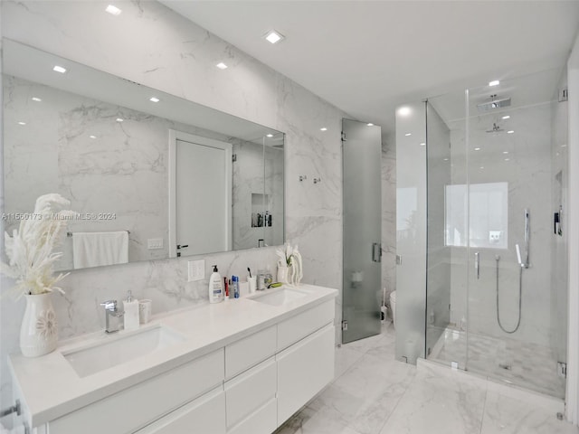 bathroom featuring tile walls, double sink, a shower with shower door, and vanity with extensive cabinet space