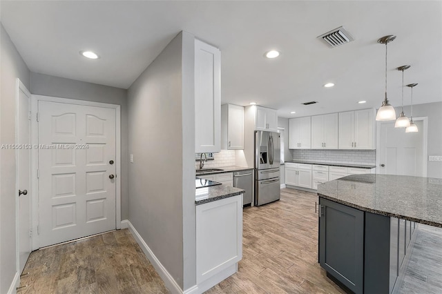 kitchen featuring appliances with stainless steel finishes, white cabinets, dark stone countertops, and light hardwood / wood-style flooring