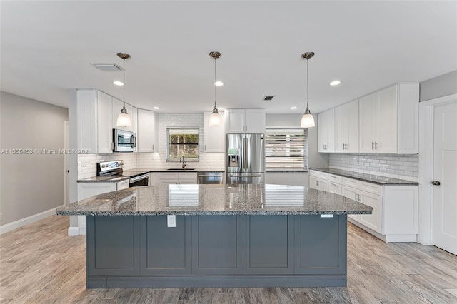 kitchen featuring a kitchen island, appliances with stainless steel finishes, white cabinetry, and tasteful backsplash