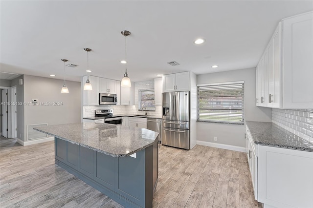 kitchen featuring light wood-type flooring, sink, appliances with stainless steel finishes, and dark stone counters