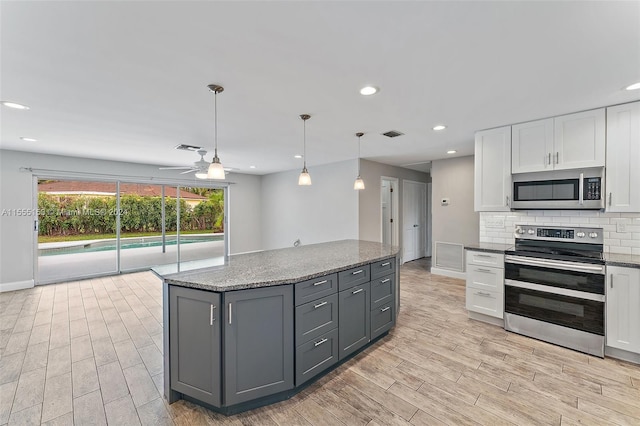 kitchen featuring dark stone countertops, white cabinetry, stainless steel appliances, ceiling fan, and gray cabinetry