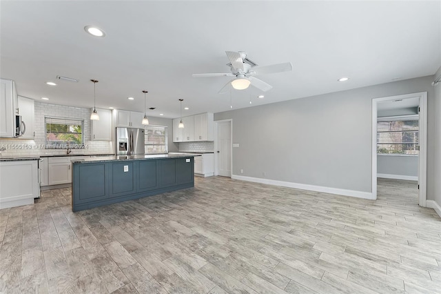 kitchen featuring appliances with stainless steel finishes, light hardwood / wood-style floors, decorative backsplash, white cabinetry, and ceiling fan