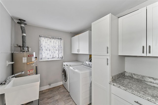 washroom with light hardwood / wood-style flooring, sink, washer and dryer, cabinets, and water heater