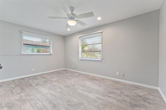 empty room featuring plenty of natural light, ceiling fan, and light wood-type flooring