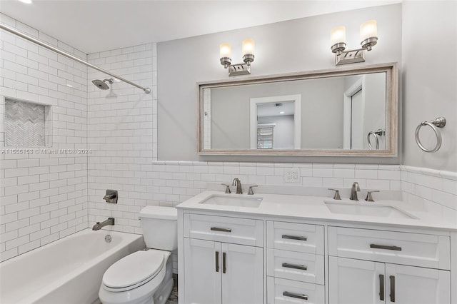 full bathroom with toilet, tiled shower / bath, vanity, backsplash, and tile walls