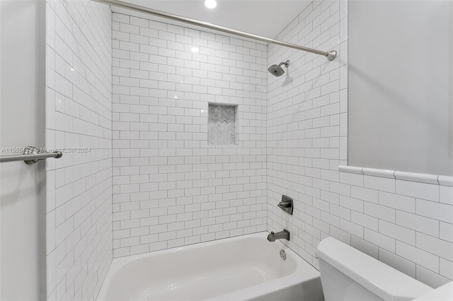 bathroom with tile walls, toilet, and tiled shower / bath