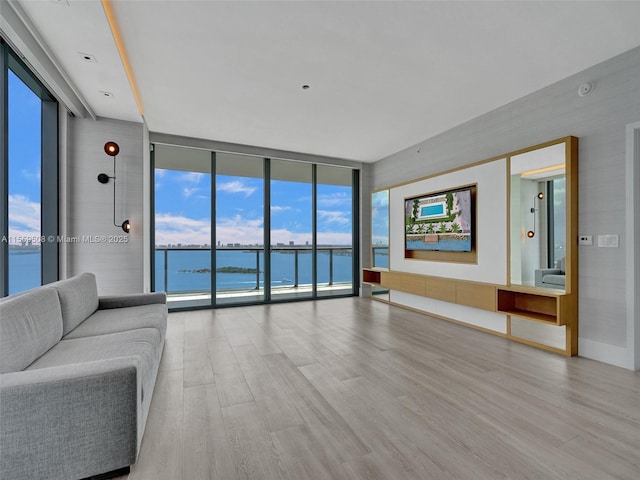 unfurnished living room with a water view, light wood-type flooring, and floor to ceiling windows