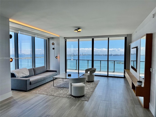 living area with floor to ceiling windows, wood finished floors, and a water view