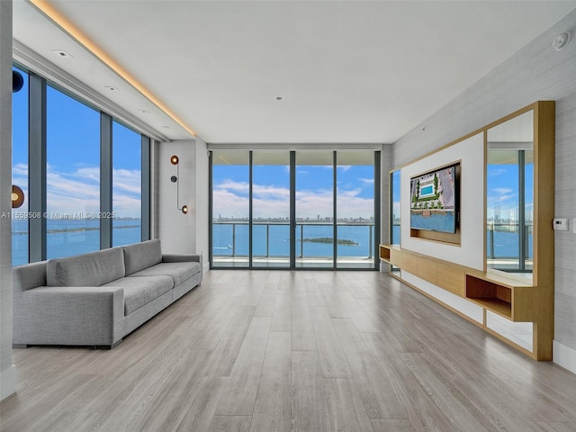 unfurnished living room with a water view, a wall of windows, and light hardwood / wood-style flooring