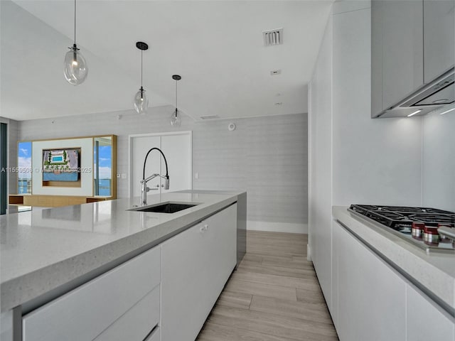 kitchen with white cabinetry, hanging light fixtures, visible vents, and a sink