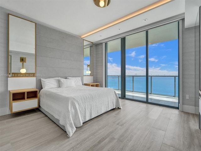 bedroom featuring expansive windows, access to exterior, and light wood-style flooring