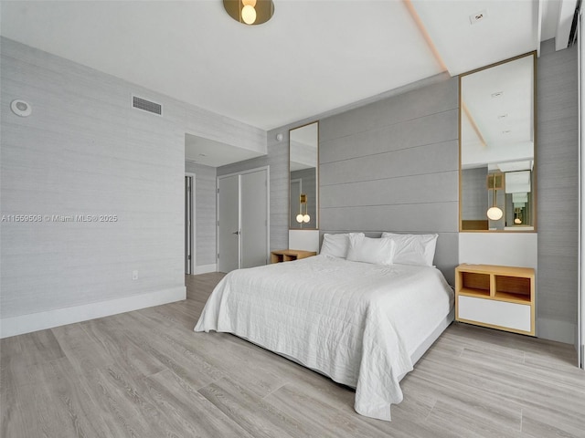 bedroom with wood finished floors, visible vents, and baseboards