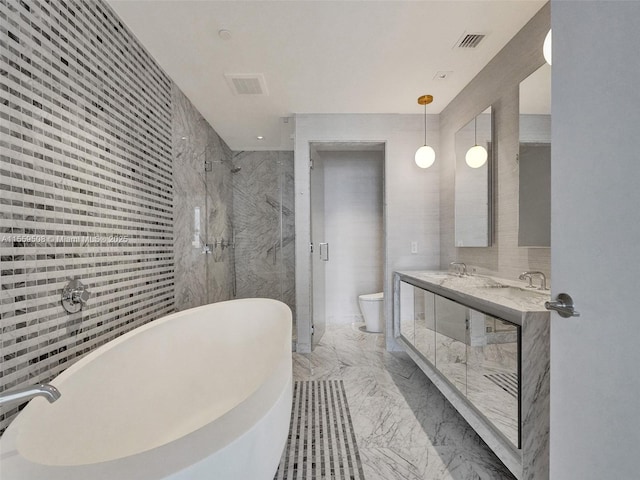 full bathroom with a shower stall, a freestanding bath, toilet, marble finish floor, and tile walls