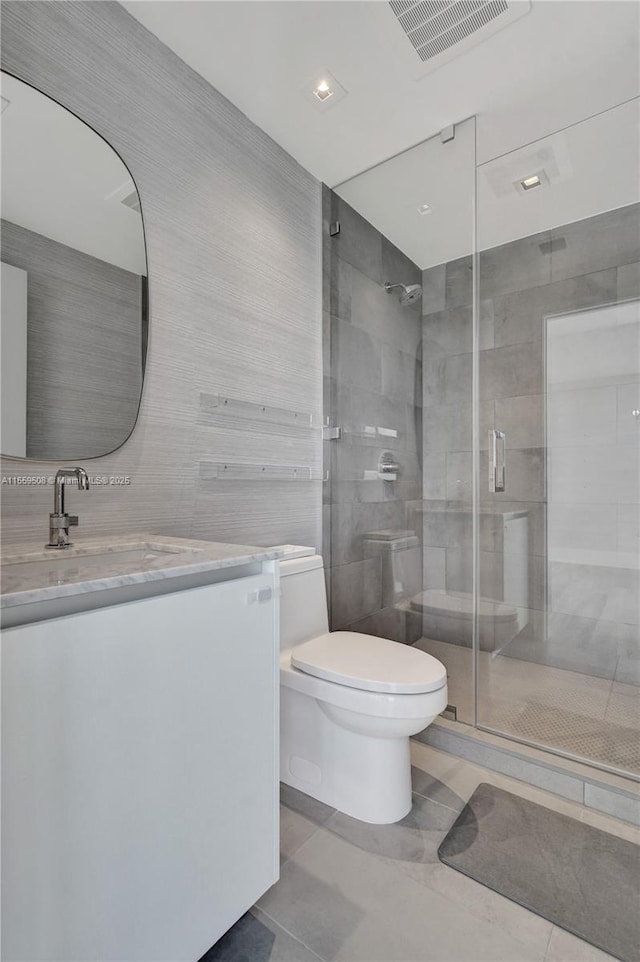 bathroom with an enclosed shower, vanity, tile walls, and toilet