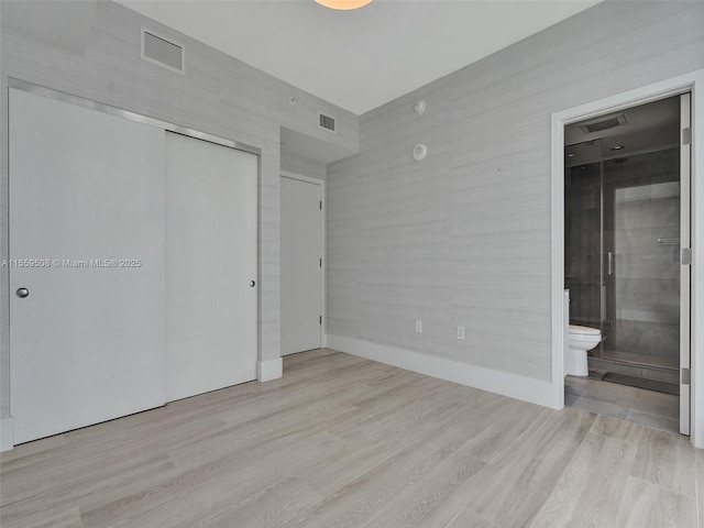 unfurnished bedroom with visible vents, a closet, and wood finished floors