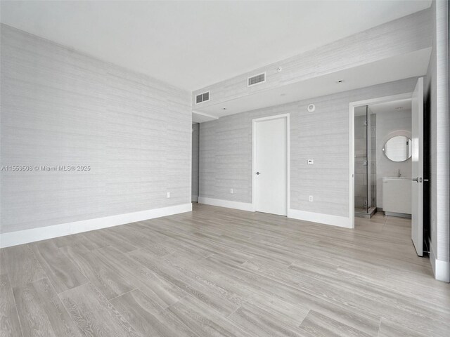 spare room with light hardwood / wood-style floors, a wall of windows, and a healthy amount of sunlight