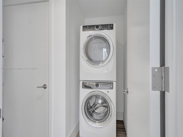 laundry area with stacked washer and dryer and dark hardwood / wood-style floors