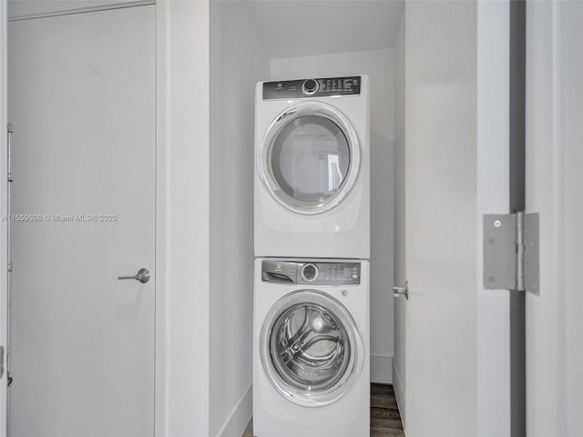 washroom featuring stacked washer and clothes dryer, wood finished floors, and laundry area