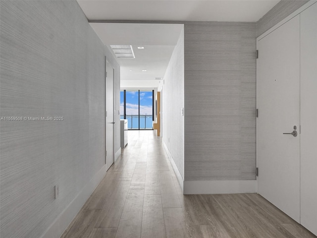 hallway with visible vents, expansive windows, and wood finished floors